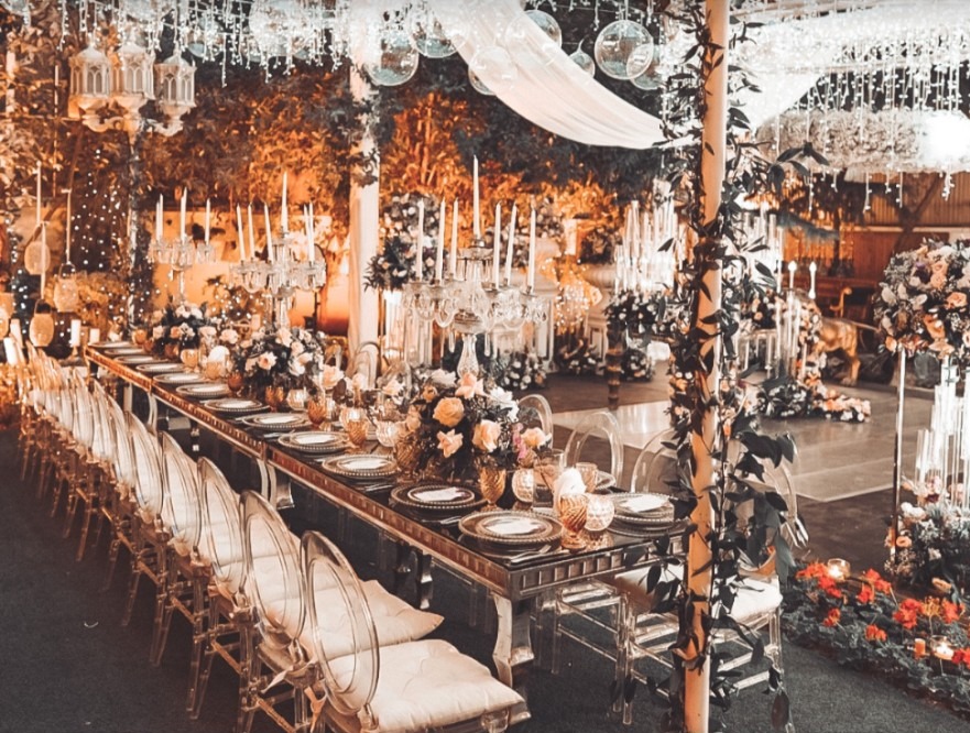 Wedding reception table with floral arrangements, crystal chandeliers and candlelight